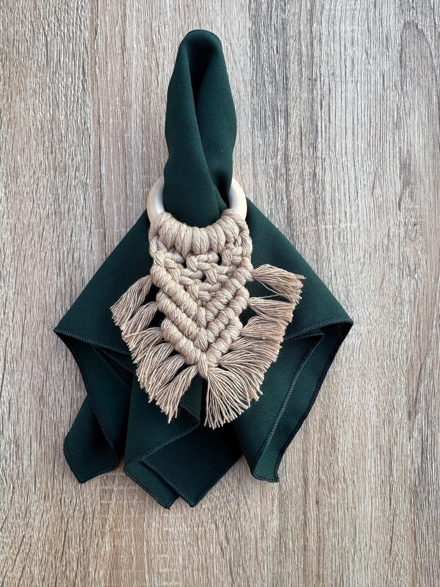 Napkin ring with macrame design on a green napkin against a wooden background