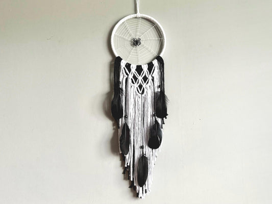 Black and white dreamcatcher hanging against a plain background