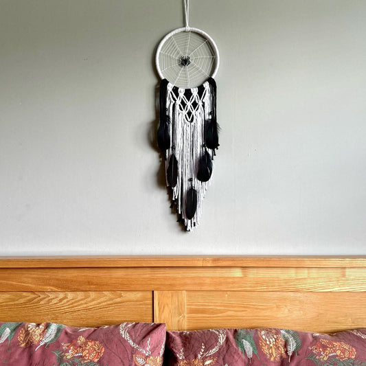 Dreamcatcher hanging above a wooden surface with a neutral background