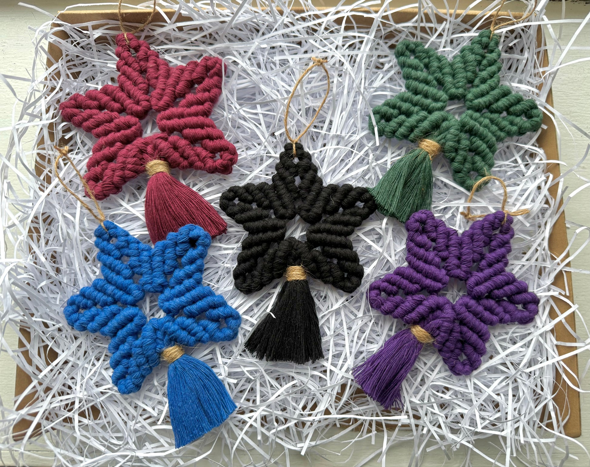 Colorful star-shaped tassel ornaments on a white shredded paper background