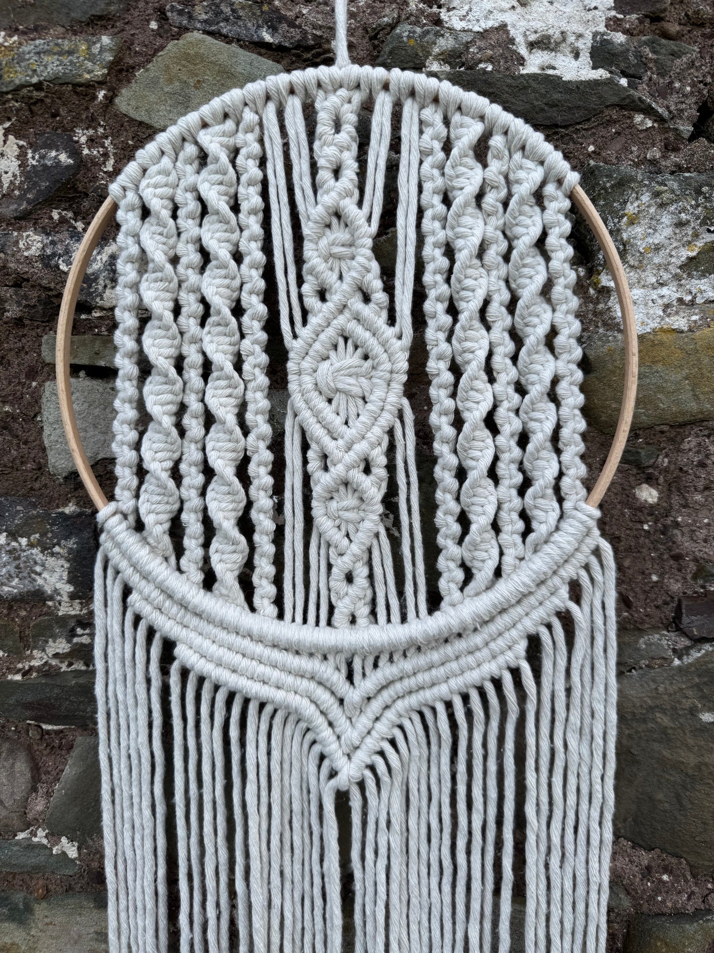 Macrame wall hanging with geometric pattern on a stone surface