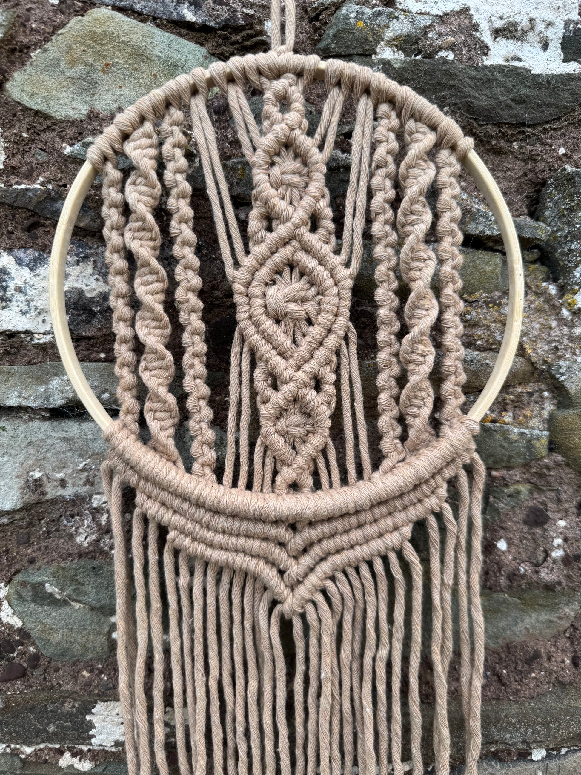 Macrame wall hanging with geometric pattern on a stone background