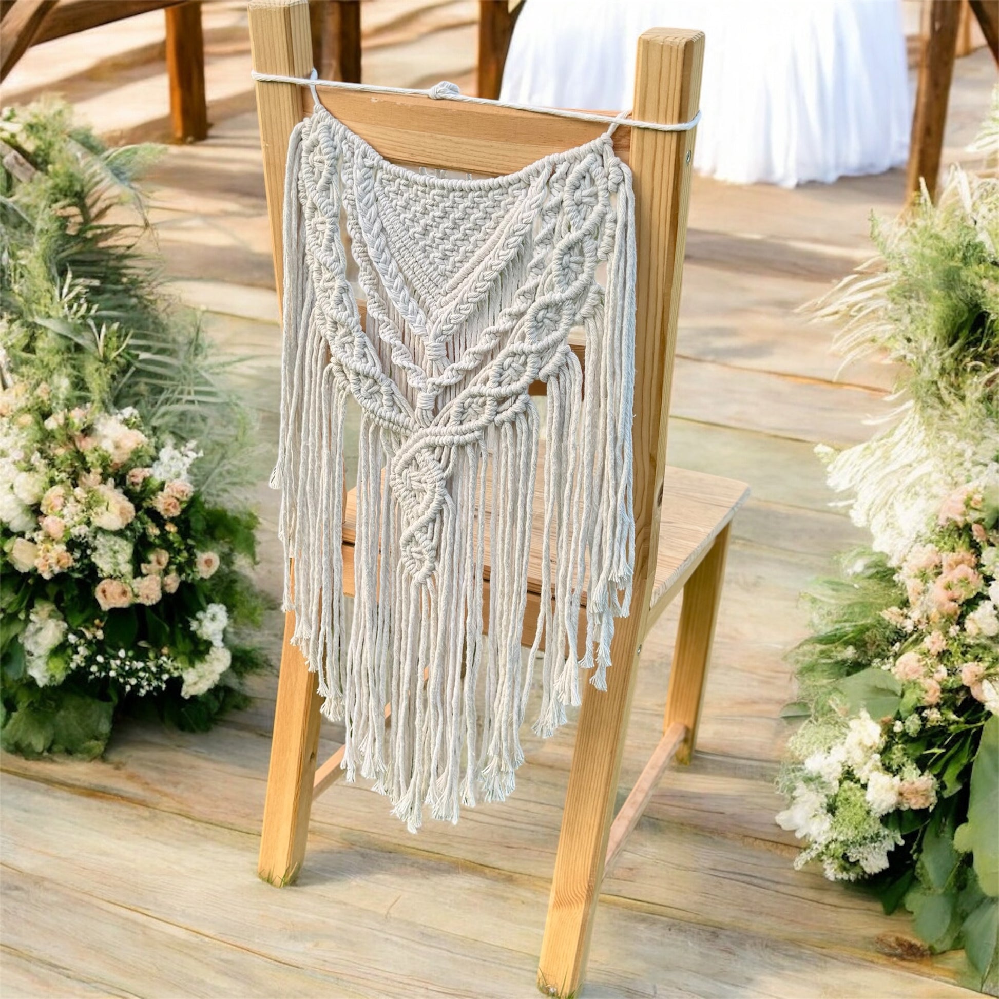 Macrame hanging on the back of a wooden chair with floral decorations on a wooden floor