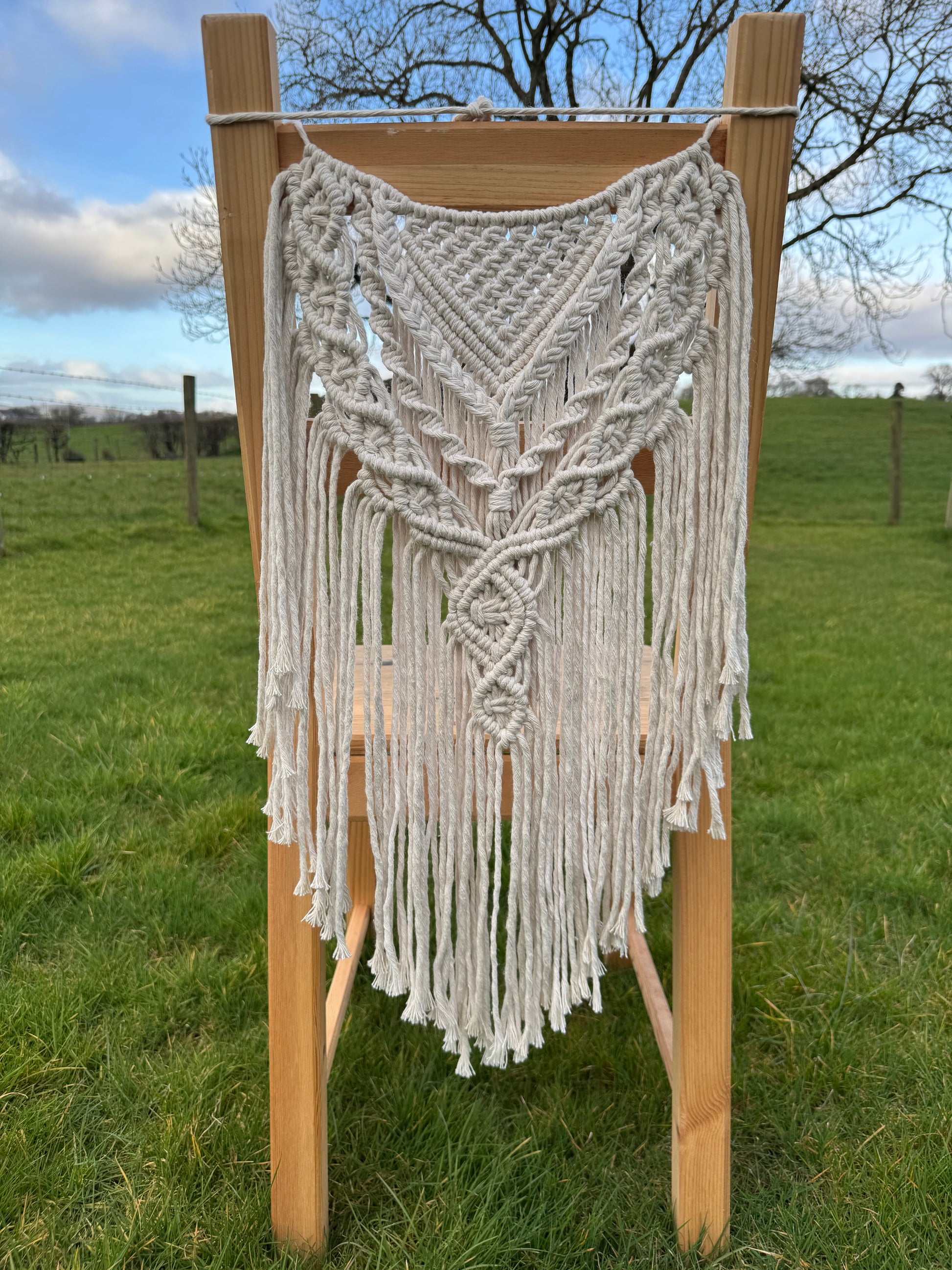 White macrame chair cover attached to the back of a chair outdoors