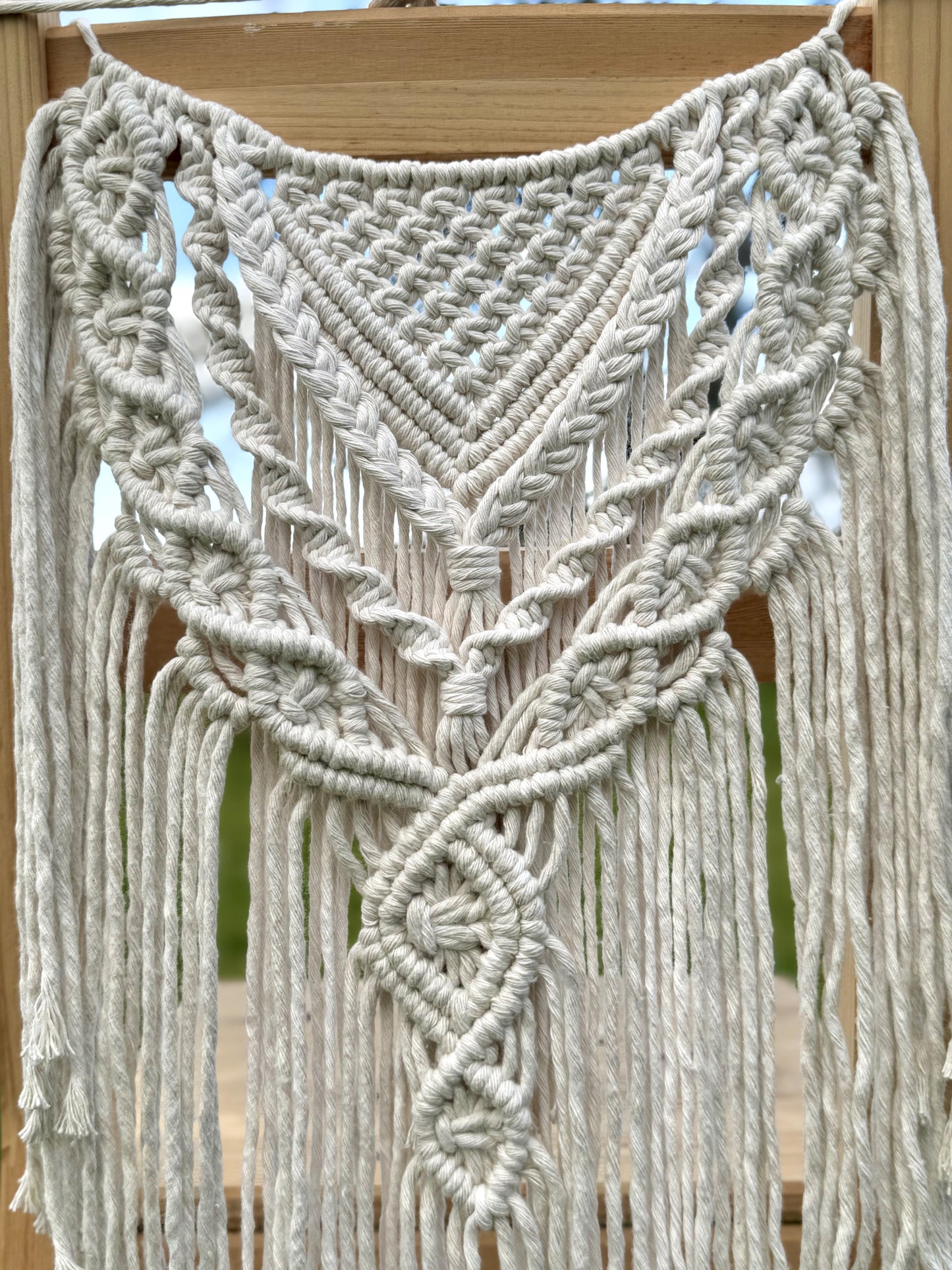 Macrame chair cover with intricate patterns and fringes on a wooden surface.