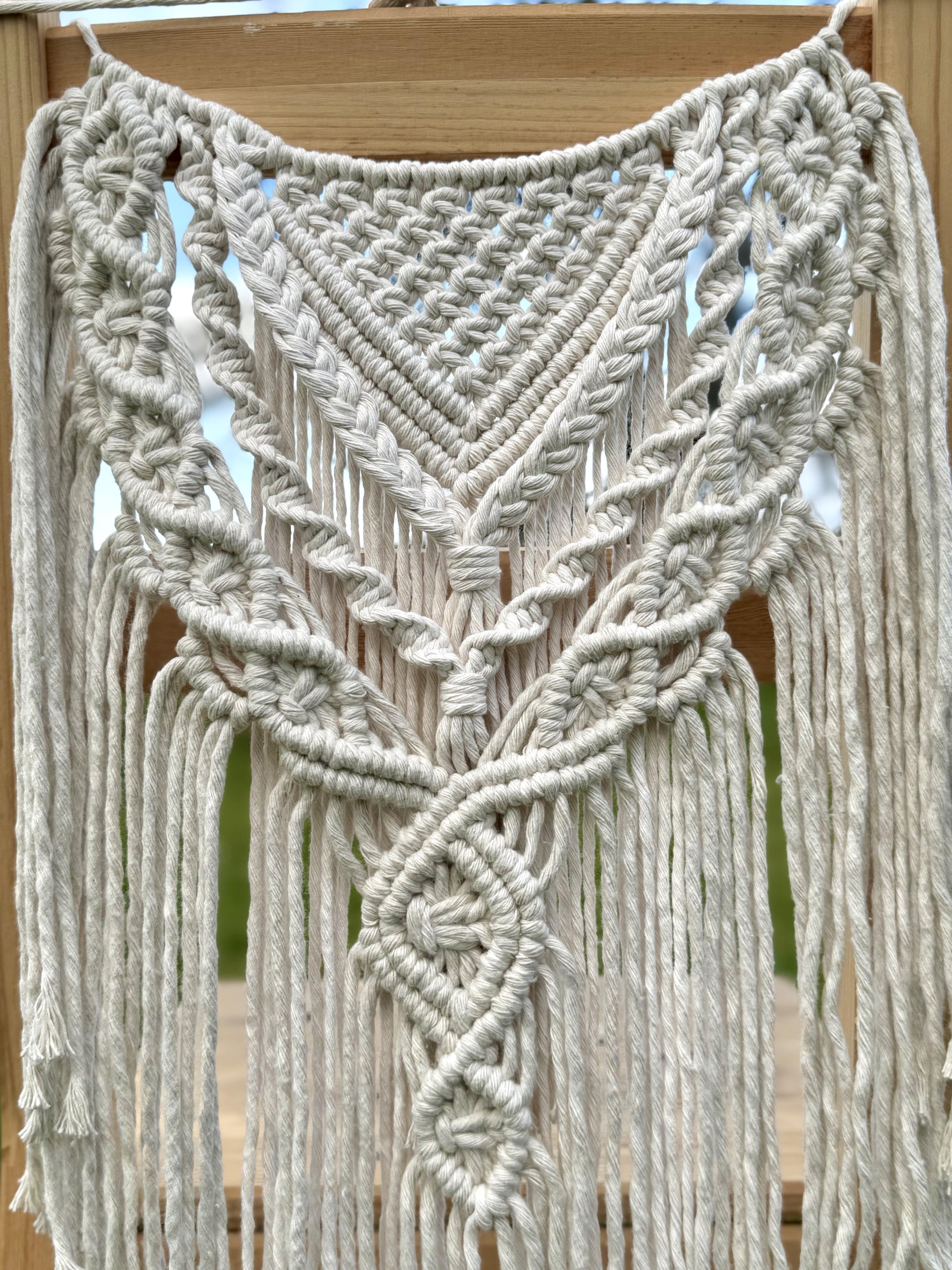Macrame chair cover with intricate patterns and fringes on a wooden surface.