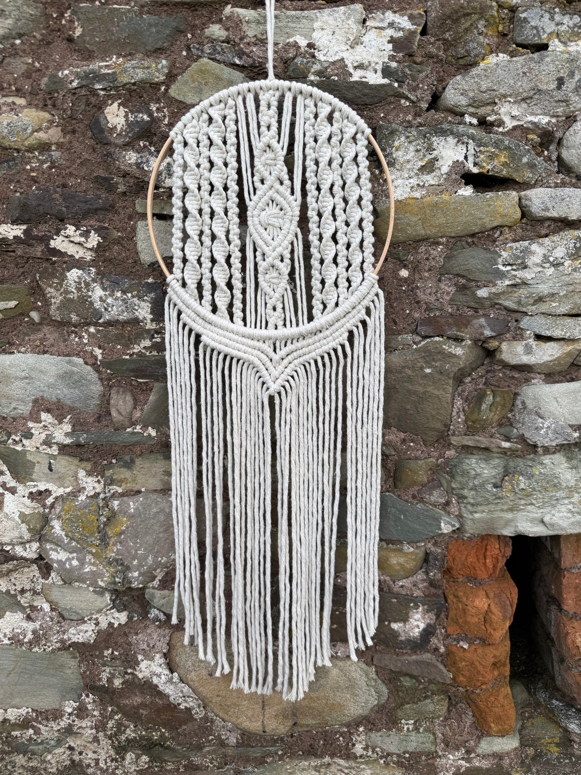 Decorative knotted wall hanging with tassels on a stone surface
