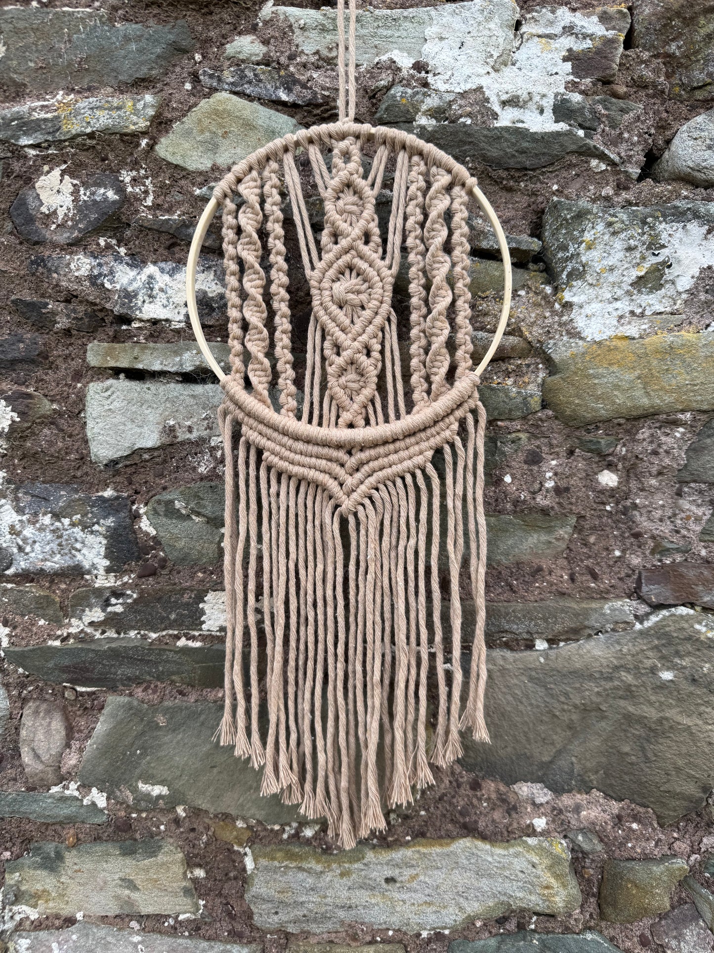 Macrame wall hanging with geometric pattern on a stone wall