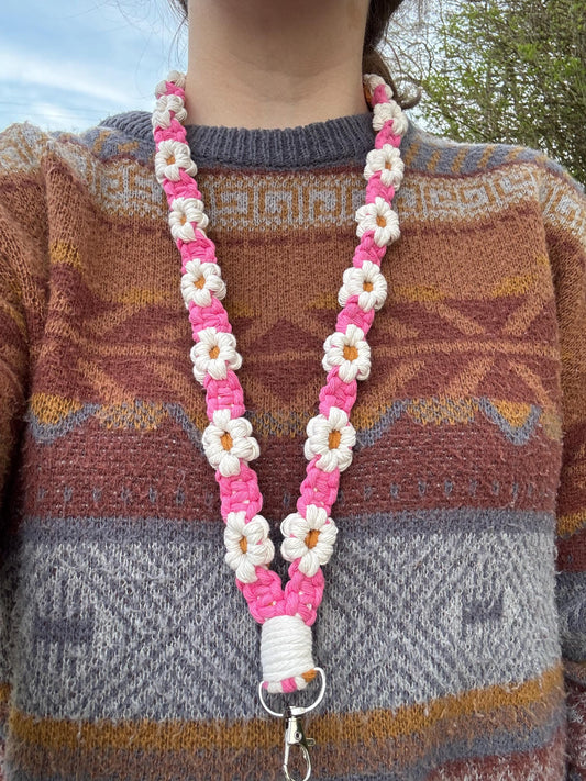 Person wearing a colorful patterned sweater with a pink and white floral lanyard.