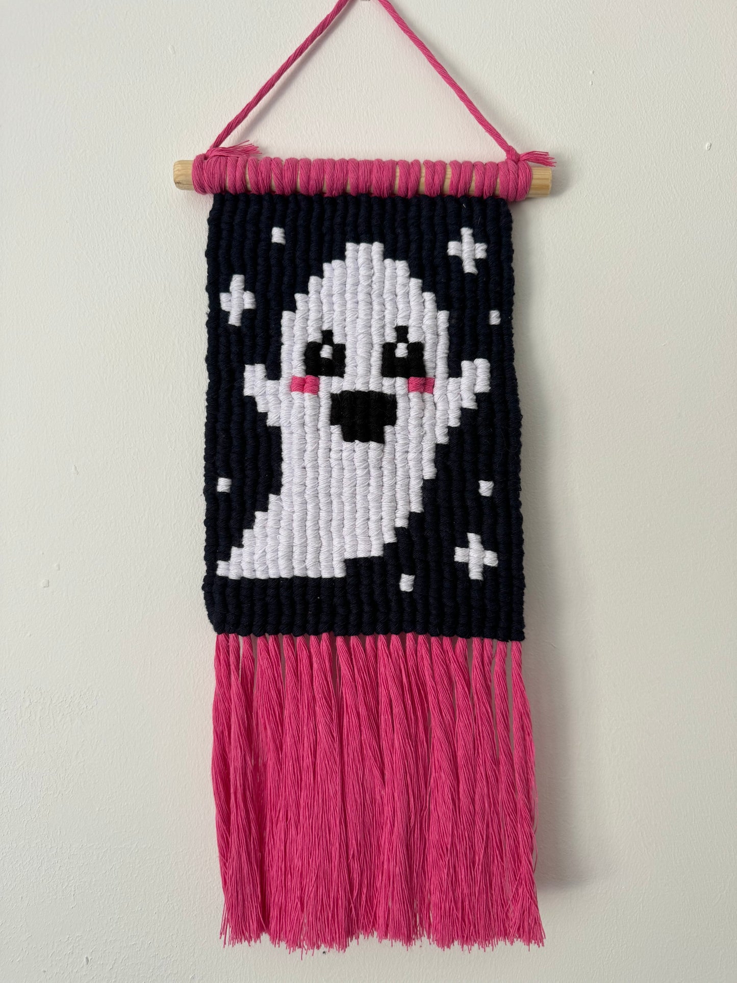 macrame wall hanging with a ghost design on a white background
