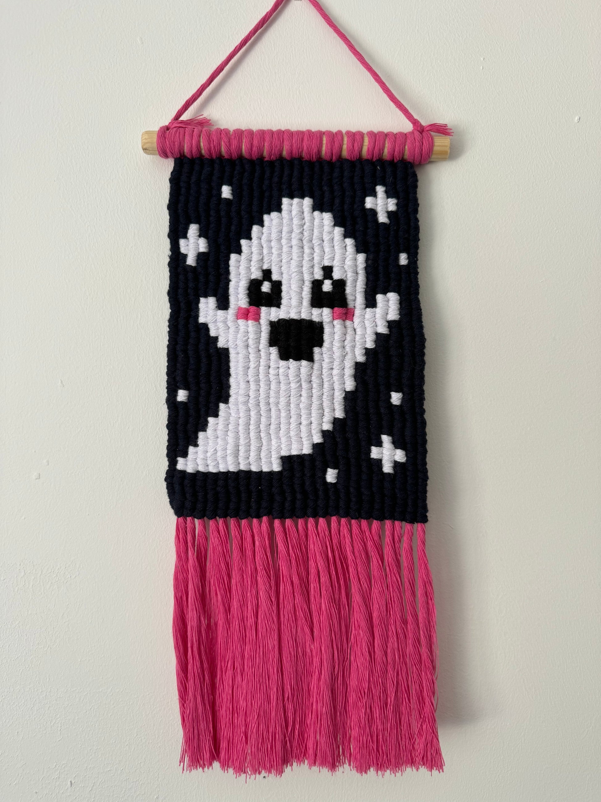 macrame wall hanging with a ghost design on a white background