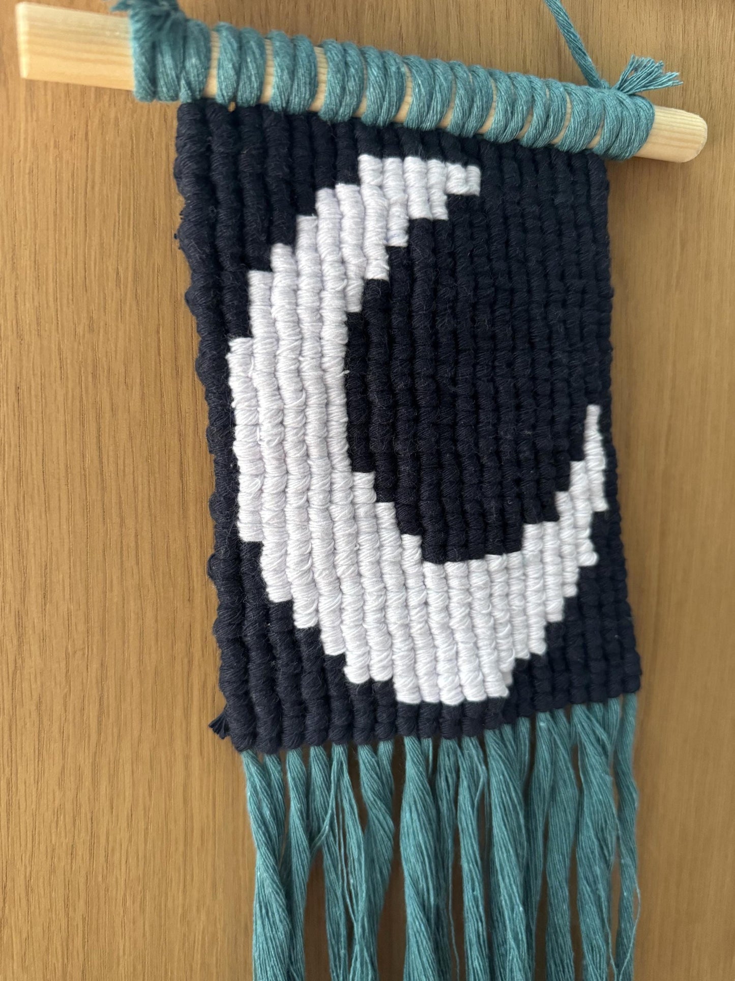 Macrame wall hanging with a moon pattern on a wooden surface