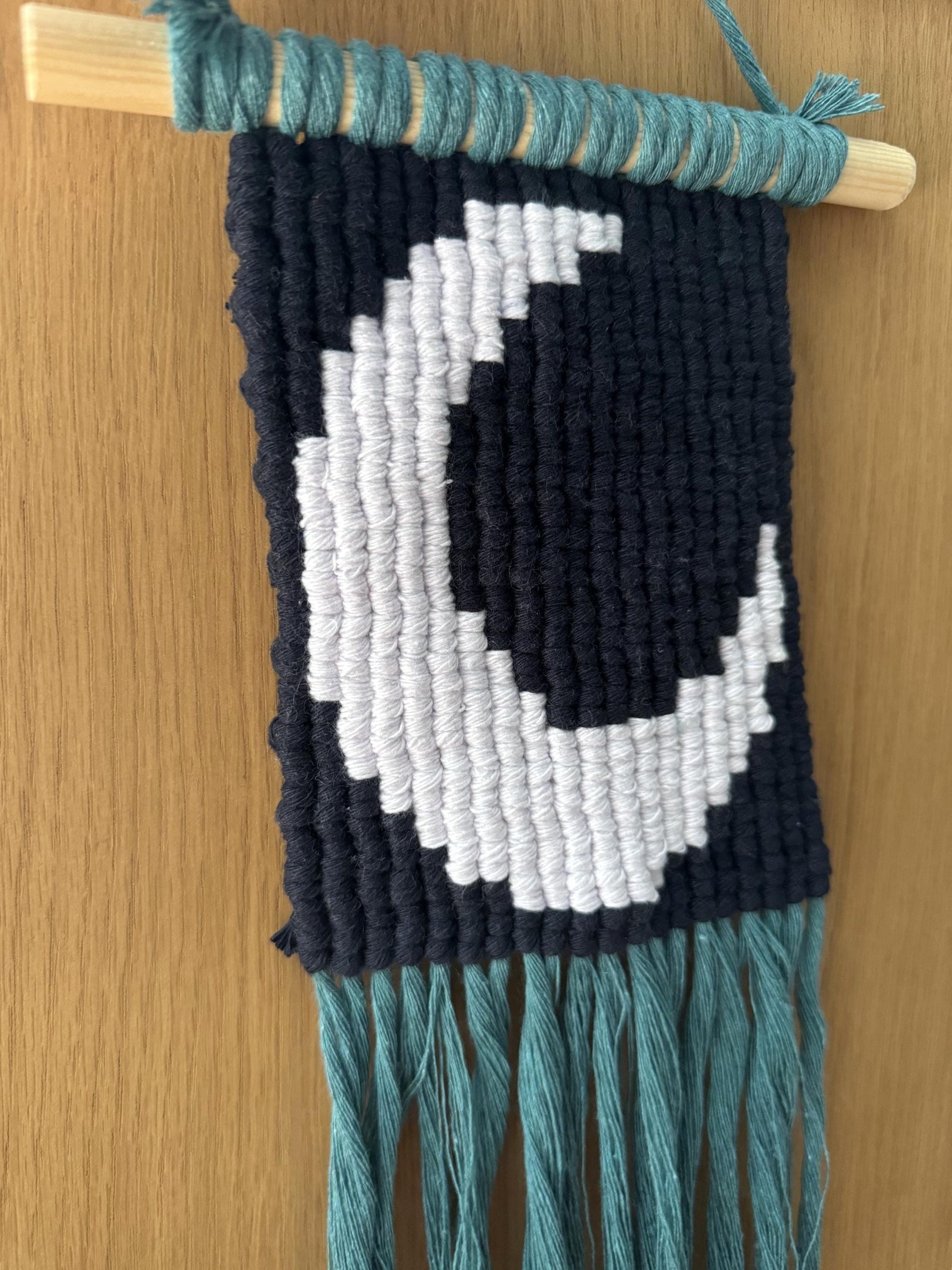 Macrame wall hanging with a moon pattern on a wooden surface