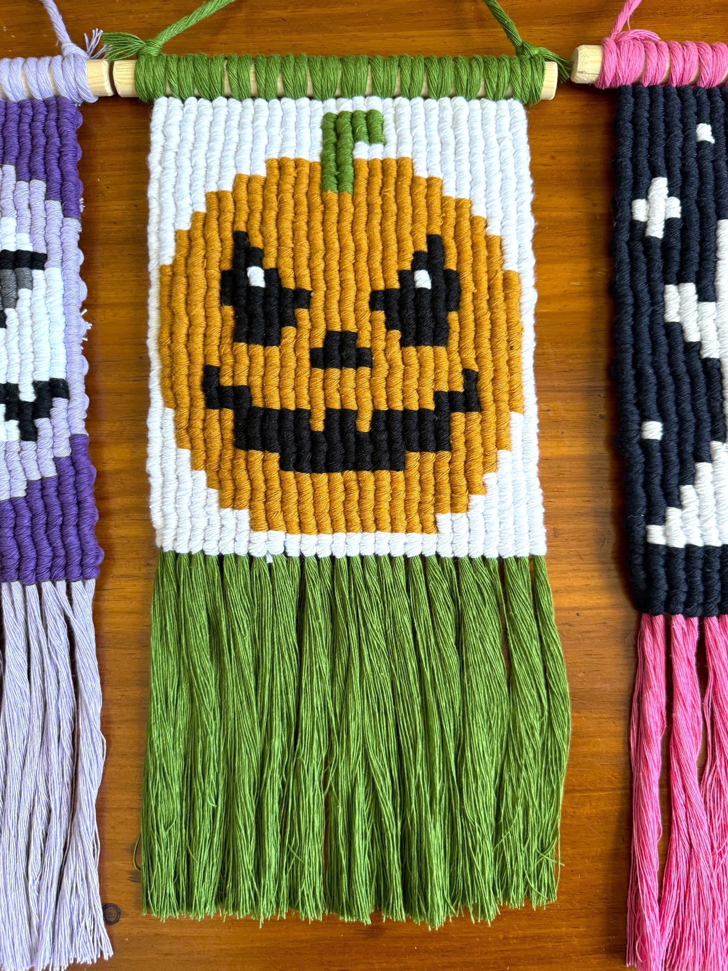 Macrame wall hanging with a pumpkin design on a wooden surface
