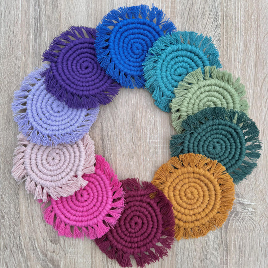 Colorful macrame circular coasters arranged in a wreath shape on a wooden surface.