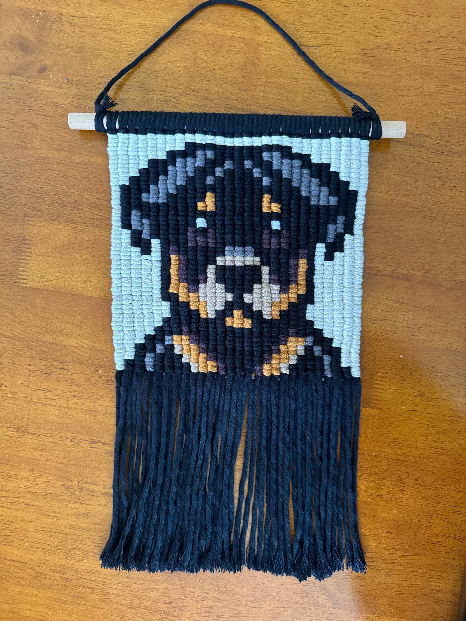 Macrame wall hanging with a Rottweiler dog design on a wooden surface