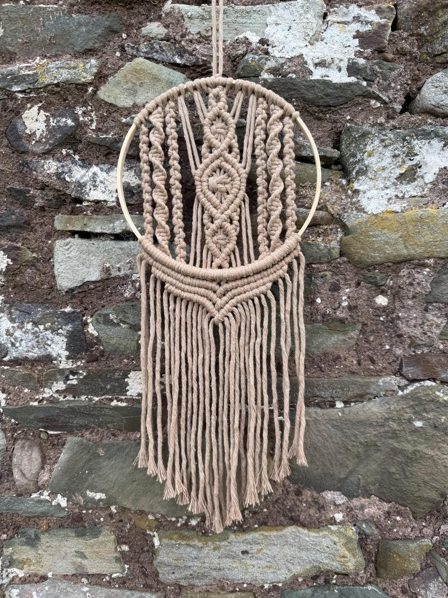 Macrame wall hanging with geometric pattern on a stone wall background