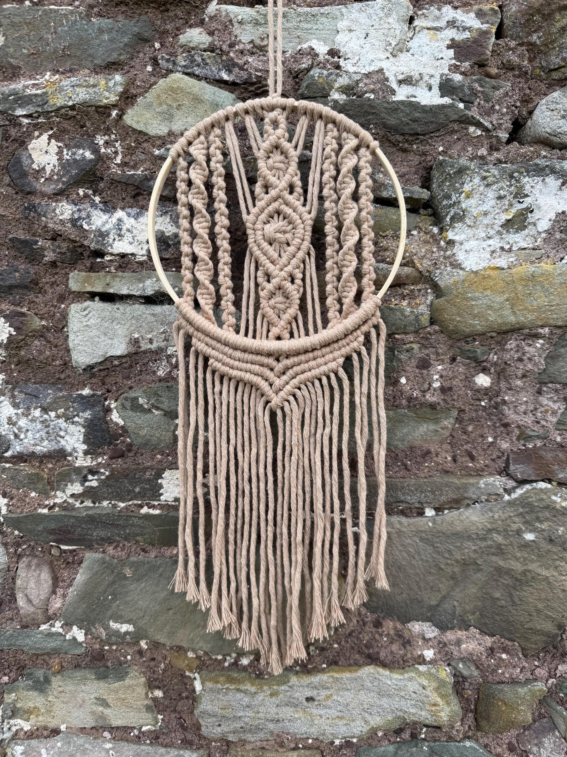 Macrame wall hanging with geometric pattern on a stone wall background