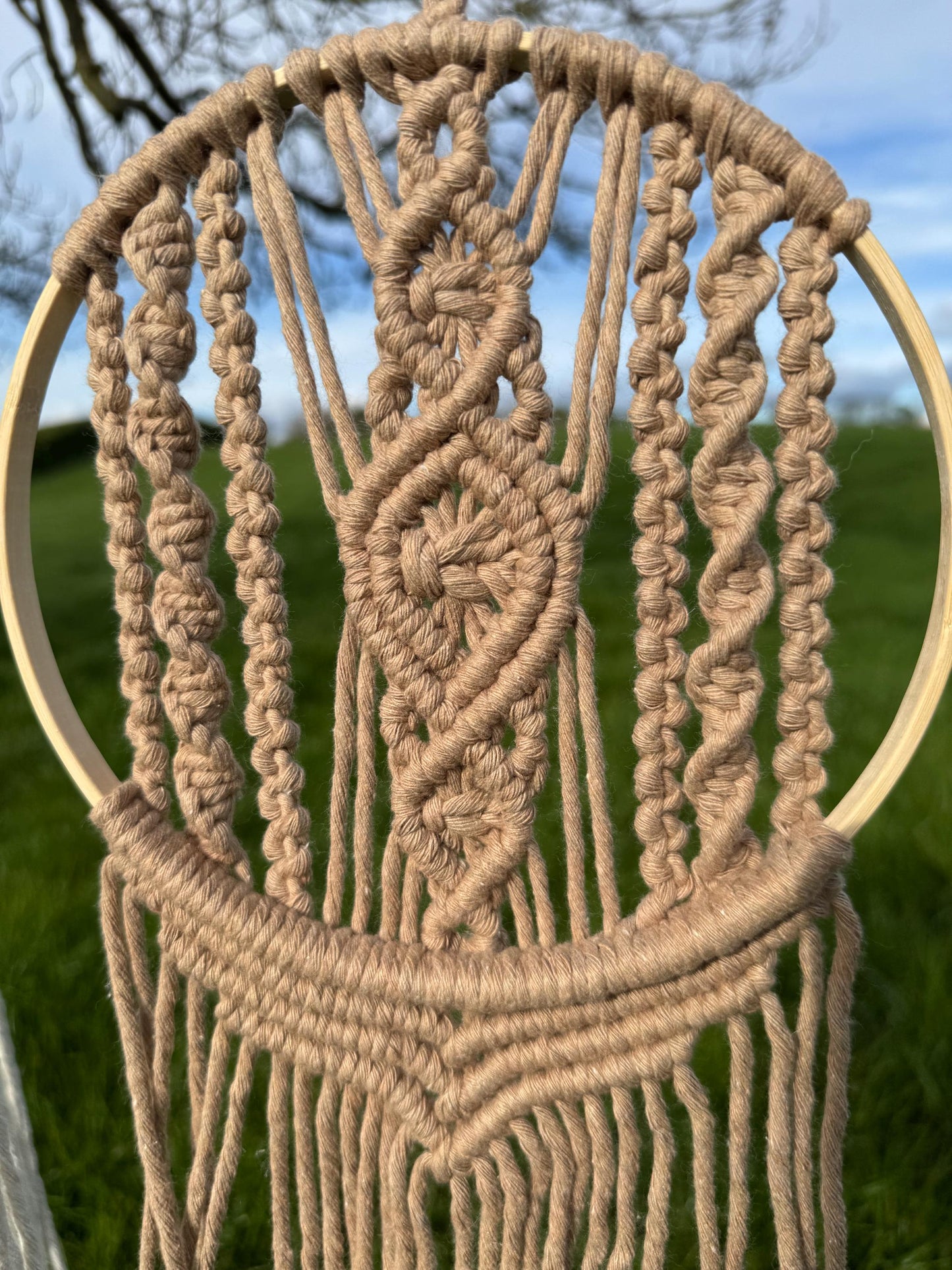 macrame wall hanging within a wooden ring