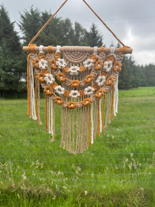 Macrame wall hanging with floral patterns in a grassy outdoor setting