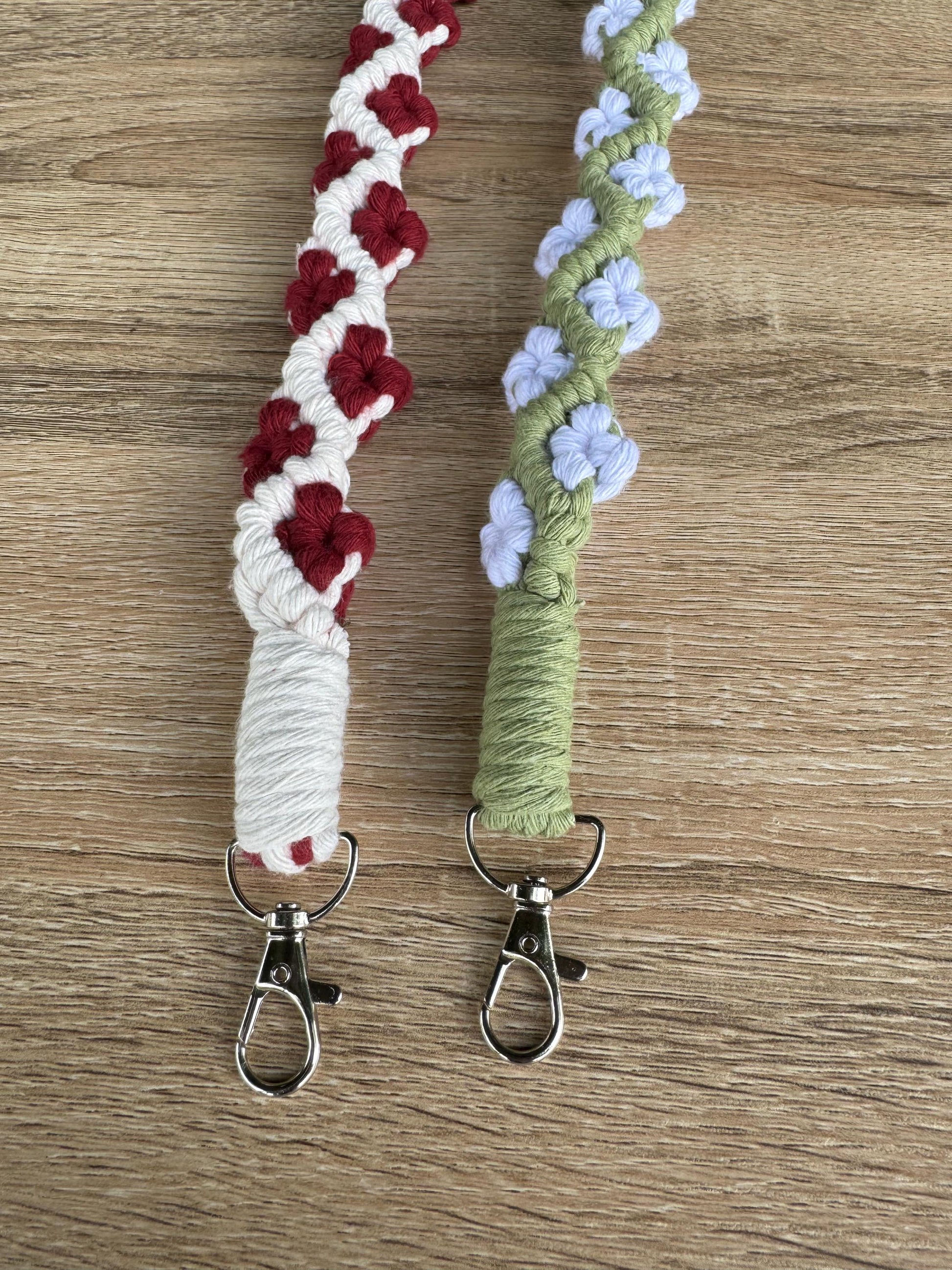 Two braided keychains with floral patterns on a wooden surface